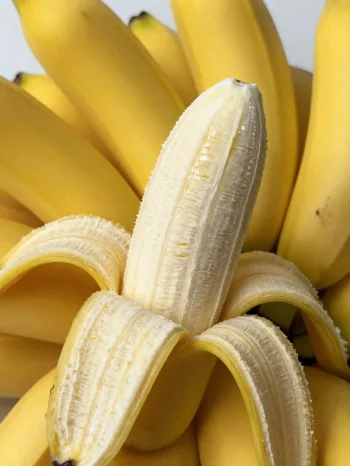 Sveža banana, cela in narezana, v skledi in na rustikalni mizi