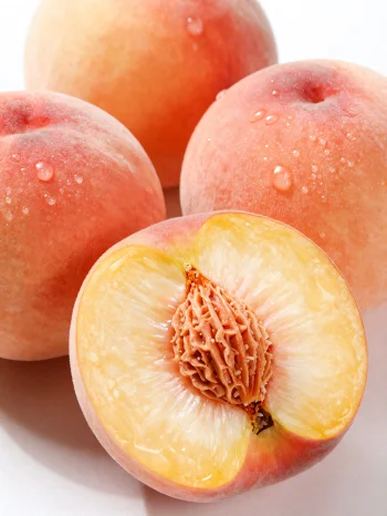 Cele in narezane breskve na leseni mizi, ob kozarcu breskovega soka