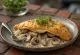 Calzone s smetano, gobami in čebulo na krožniku