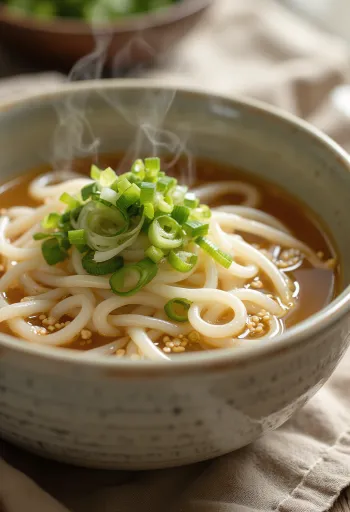 Kake udon osnovna udon juha v skledi z dashi osnovo, okrašena s svežo mlado čebulo in sezamovimi semeni
