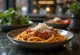 Špageti bolognese, potreseni s svežo baziliko in parmezanom