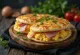 Jajčna pita za zajtrk, postrežena s šunko, papriko, paradižnikom in naribanim sirom