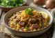 Haleem s praženo čebulo, postrežen z bogatimi začimbami in svežim koriandrom